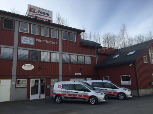 Rød bygning med Arendal EL Teams firmabiler